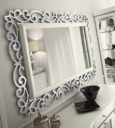 a mirror on the wall above a dresser in a room with white walls and furniture