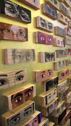 a woman standing in front of a wall covered with wooden boxes and eyeballs on them