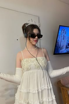 a woman in white dress wearing headphones and holding out her arms