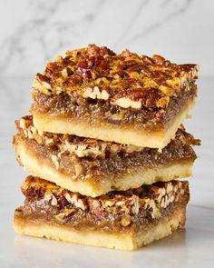 three pieces of pecan bar stacked on top of each other in front of a marble background