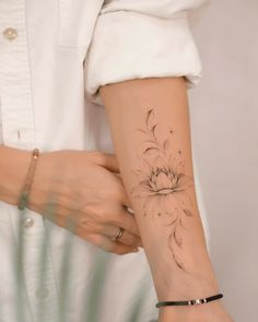 a woman's arm with a flower tattoo on the left side of her arm