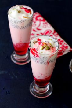 two glasses filled with dessert sitting on top of a table