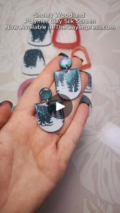 someone is holding some rings in their hand with pine trees on them and snow woodland