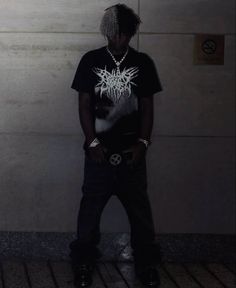 a man standing in front of a wall wearing a black shirt with white writing on it