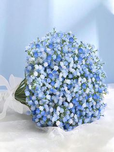 a bouquet of blue flowers sitting on top of a white tablecloth covered table cloth