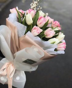 a bouquet of pink and white tulips wrapped in paper