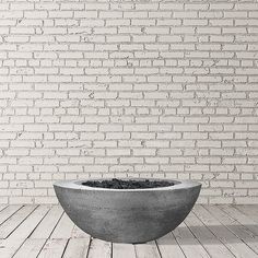 a concrete bowl sitting on top of a wooden floor next to a white brick wall