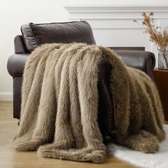 a chair with a blanket on top of it next to a fire place in a living room