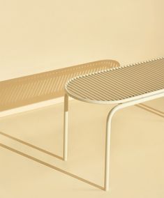 a white bench sitting on top of a floor next to a beige wall with shadows