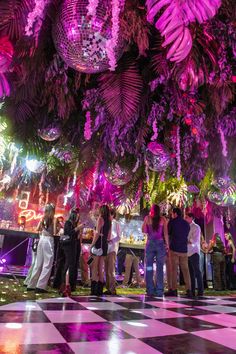 people are standing in the middle of a dance floor with disco balls hanging from the ceiling