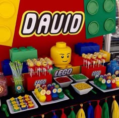 a table with lego themed desserts and candies in front of a sign that says david