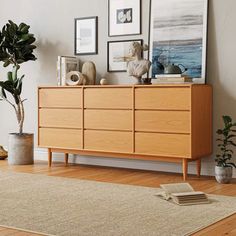 a wooden dresser sitting on top of a hard wood floor next to a potted plant