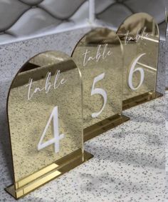 three gold glass table numbers on top of each other