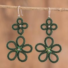 a pair of green crochet earrings hanging from a branch