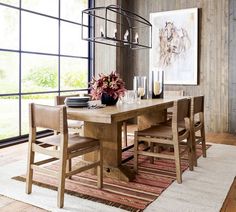 a dining room table and chairs in front of a large window with an area rug on the floor