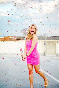 a woman in a pink dress is throwing confetti on her head and smiling