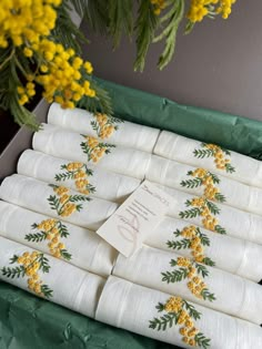 napkins with yellow flowers on them are in a green box next to some yellow flowers