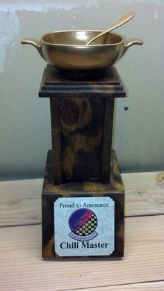 a metal bowl sitting on top of a wooden stand next to a sign that says chili master