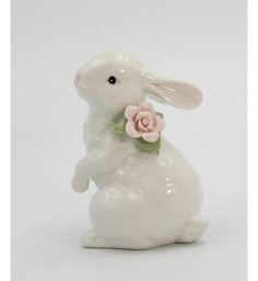 a white ceramic rabbit with a pink rose in its mouth