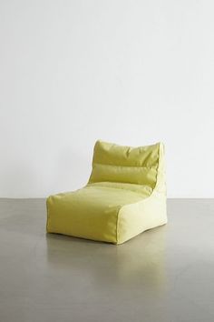 a yellow chair sitting on top of a cement floor next to a white wall in an empty room