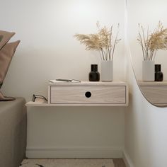 two vases with flowers are sitting on a small table in front of a mirror