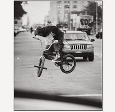 a man on a bike is doing a trick in the air over a street with cars