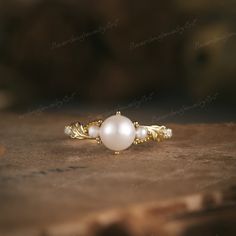 a close up of a pearl ring on a wooden surface with other items in the background