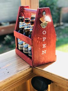 an open wooden beer caddy with six bottles in it sitting on a table outside