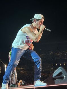 a man standing on top of a stage while holding a microphone in his right hand