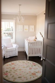 a baby's room with a white crib, rocking chair and chandelier