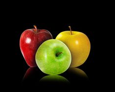 two apples sitting next to each other on a black surface with reflection in the middle