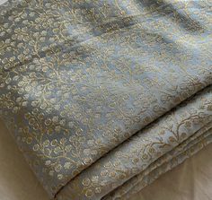 two pieces of blue and gold brocaded fabric folded on top of each other