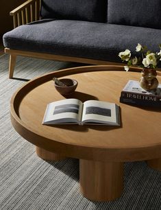 a coffee table with an open book on it and flowers in a vase next to it