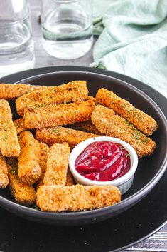 a plate full of fried food with ketchup and sauce on the side for dipping