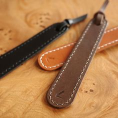 two brown and black leather straps sitting on top of a wooden table