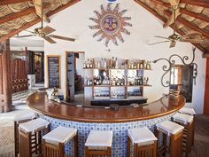 a bar with several stools in front of it and a ceiling fan hanging from the ceiling