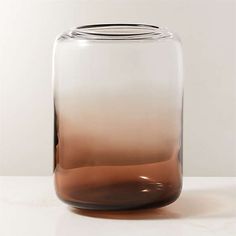 a brown and white glass vase sitting on top of a table next to a wall