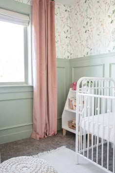 a baby's room with floral wallpaper and pink curtains