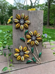 three yellow and green flowers sitting on top of a wooden board next to some grass