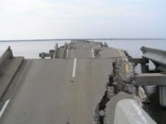 a road that has been partially submerged in the water and is being blocked off by concrete barricades