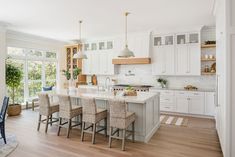 a large kitchen with white cabinets and wooden flooring, along with a breakfast nook