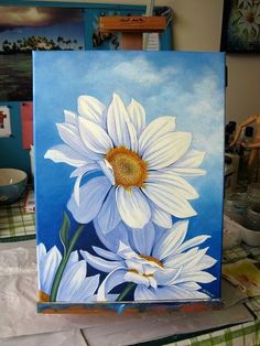 a painting of white daisies on a blue background with other paintings in the background