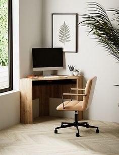 a desk with a computer on it in front of a window and a potted plant