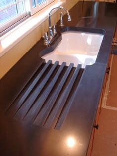 a black counter top with a white sink and faucet next to it in front of a window