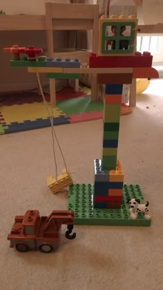 a toy truck is parked in front of a lego structure with a crane attached to it