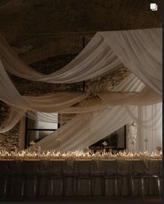 the table is covered with white draping and flowers