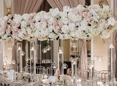 a table with flowers and candles on it in front of a mirror wall filled with chandeliers