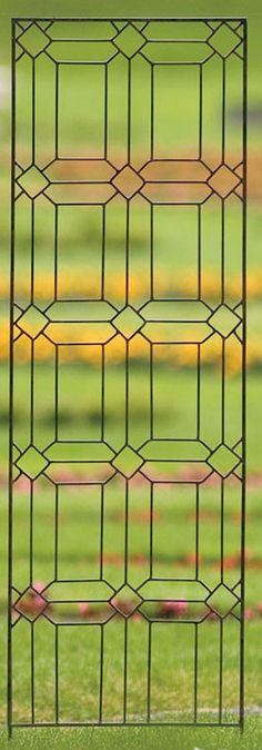 an iron fence with green grass in the background