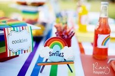 a table topped with lots of colorful food and drinks next to a rainbow themed box