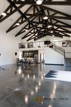 a large open space with high ceilings and wooden beams on the ceiling is lit by spotlights